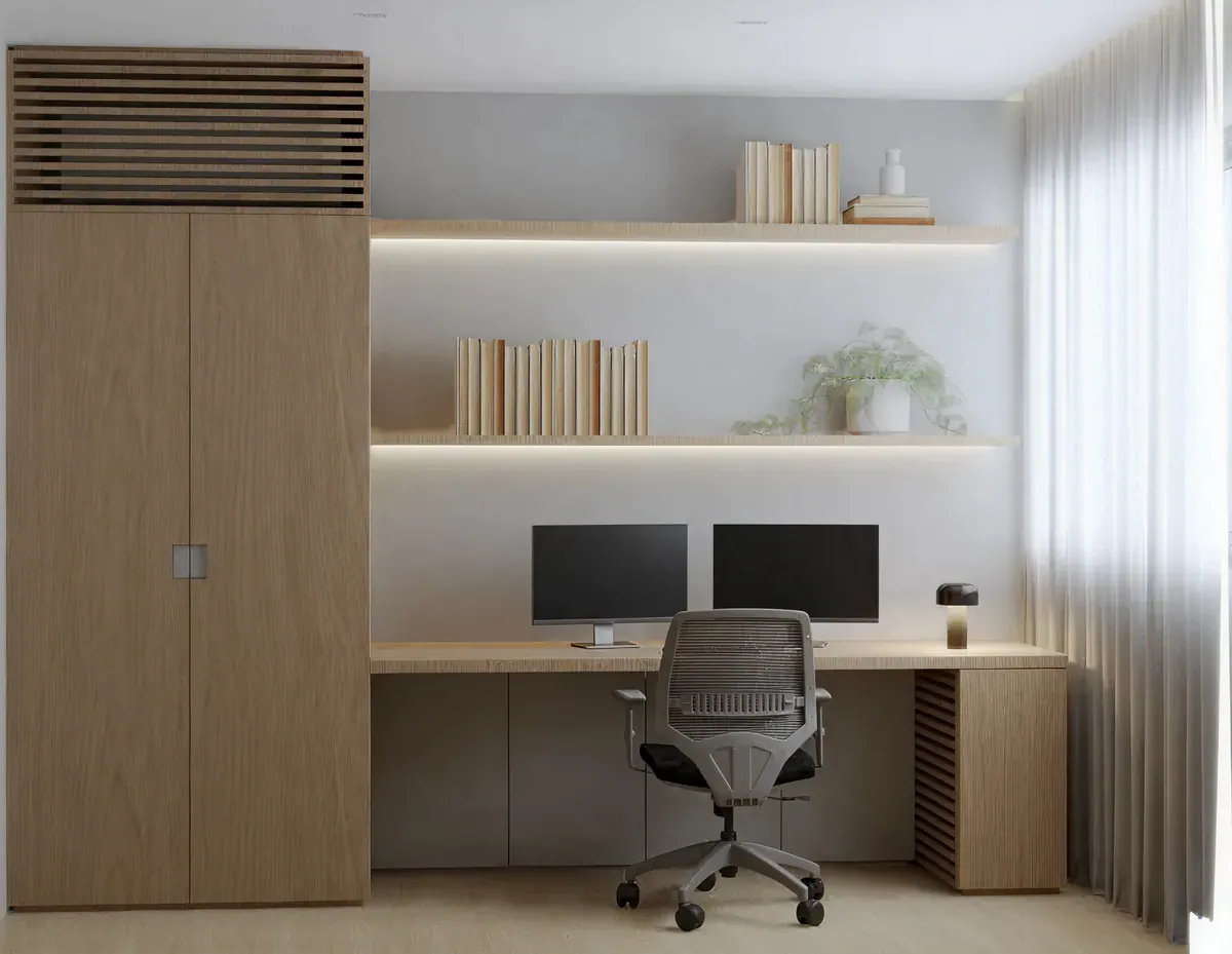 Home office com bancada para dois monitores, prateleiras iluminadas e armário de madeira