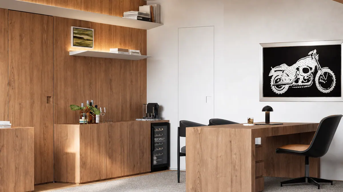 Aparador de madeira com bar e adega, mesa de trabalho e quadro da moto ao fundo